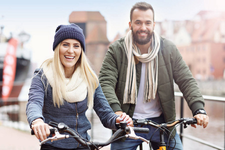 年轻夫妇骑自行车和玩在城市图片