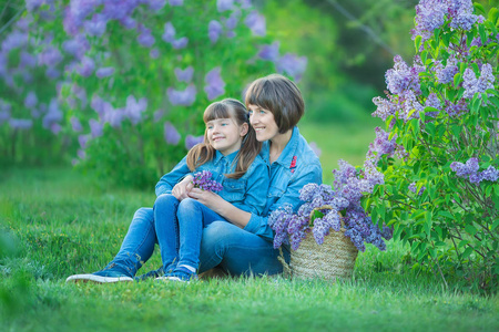 逗人喜爱的可爱的美丽母亲夫人妇女与黑发女孩女儿在淡紫色灌木的草甸。穿牛仔裤的人