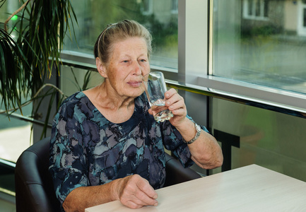 老妇饮用水从玻璃