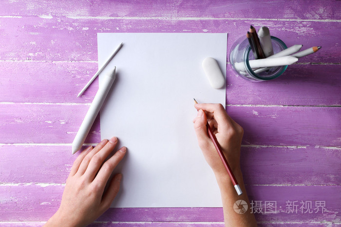 彩色铅笔与张空白的纸木制的桌子上的手
