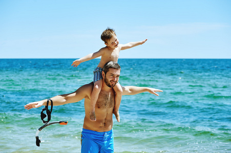 父亲和儿子在沙滩上水下设备。父亲教儿子如何游泳