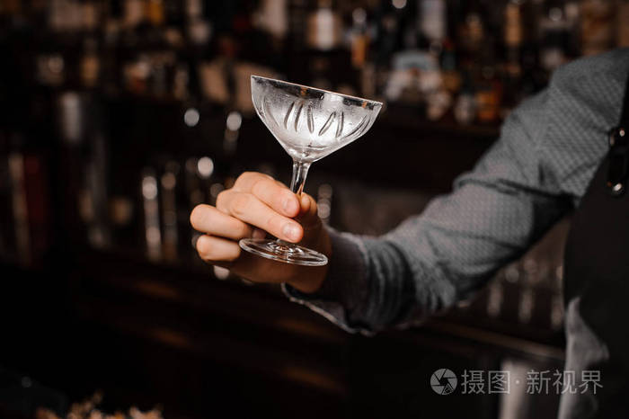 酒吧招待手拿着一个空的鸡尾酒玻璃照片-正版商用图片