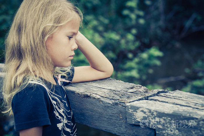 坐在桥上悲伤的金发小女孩的画像