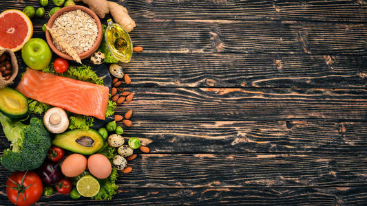 健康食品。鱼鲑, 鳄梨, 花椰菜, 新鲜蔬菜, 坚果和水果。在木制背景上。顶部视图。复制空间