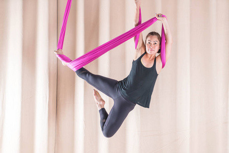 亚洲妇女训练在健身室与飞行瑜伽元素