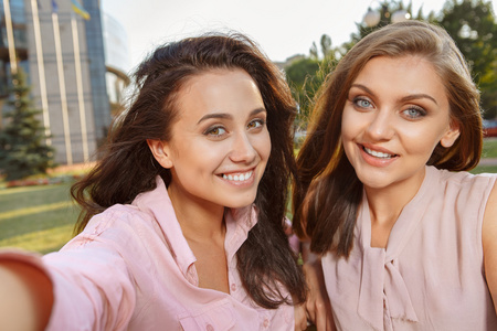 两个女孩坐在板凳上使自拍照