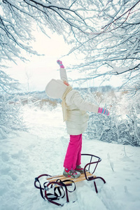 美丽的小女孩在冬天在雪中。冬季滑雪橇。文本位置