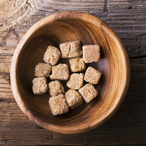 多维数据集天然棕色糖在背景上的木碗。有机食品的概念。选择性的焦点