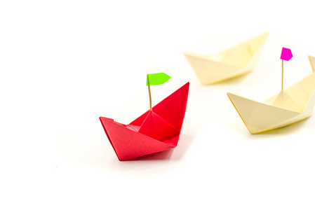 带有旗子的折纸纸船跟随其他船. 领导企业理念