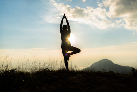 亚洲女人练习瑜伽的战士在日落时