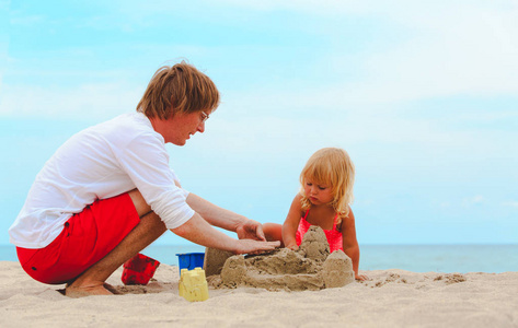 父亲和小女儿在海滩玩玩沙子