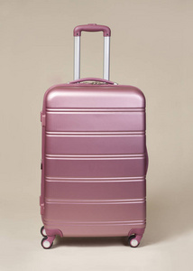 米色背景下的粉红色手推车手提箱