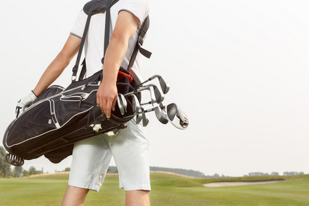 男子携带他的高尔夫球袋跨课程