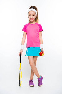 可爱的小女孩拿着网球拍和球和微笑在照相机