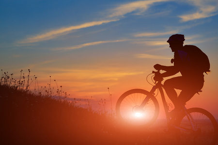 一个骑自行车的人和自行车上日落背景的剪影