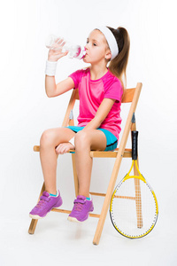 可爱的小网球运动员坐在木椅和饮用水