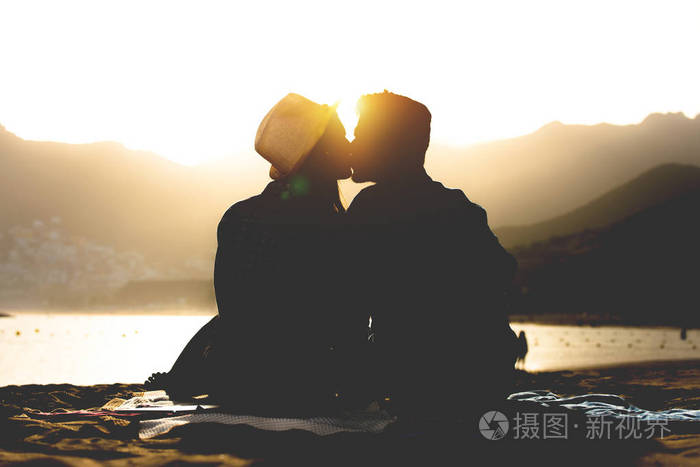 浪漫的年轻情侣亲吻在海滩上日落-青少年恋人的剪影在