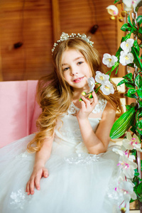 一个美丽的小女孩穿着一个夏天的白色礼服, 长卷发, 坐在秋千