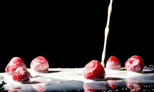 草莓制作 A 飞溅。黑色背景上的孤立。宏观照片的草莓牛奶中喷溅和滴眼液