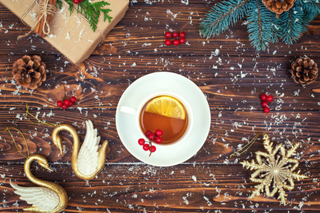 带有圣诞装饰品的木制背景。一杯加柠檬的热茶。圣诞节日贺卡。新年假期概念