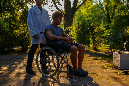 男人在轮椅和他在公园里的医生