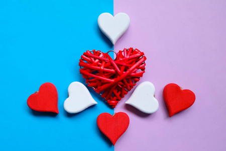蓝色和紫色背景上红色木制手工心脏符号的顶部视图。两个色调柔和的背景。情人节主题