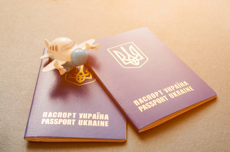 阳光下躺在乌克兰护照上的一架小玩具飞机