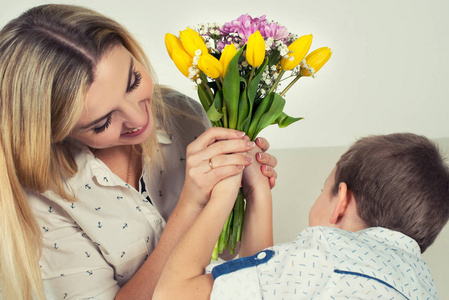 儿子送给心爱的母亲一束美丽的郁金香。庆祝的概念, 妇女节