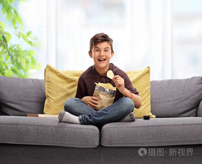 小男孩坐在沙发上吃薯片