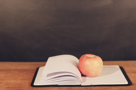 苹果和已打开的书与黑板背景