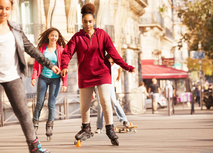 在城市边散步的锥体周围的非洲少年女孩轮滑