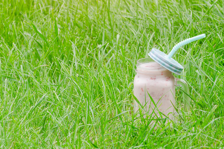 绿草背景下的酸奶杯。文本空间