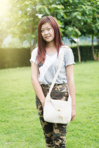 亚洲的年轻女孩与袋站在公园上的肖像