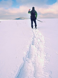 雪与背包拍照通过智能手机的人。徒步旅行者在雪堆里