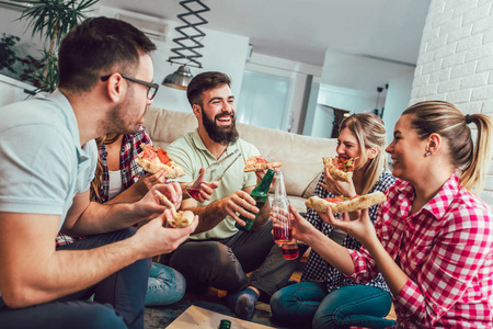 一群年轻的朋友吃比萨饼。家庭聚会快餐概念