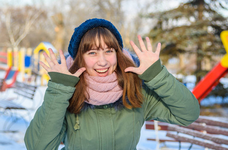 年轻姑娘调皮地笑抬起她的手在冬天在公园特写