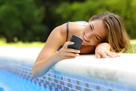 在夏天在池畔使用智能手机的女人