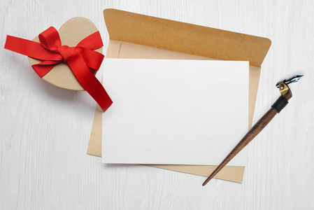 样机书法羽毛信封与信件和礼物与红色弓, 贺卡为情人节与地方为您的文本。平躺, 顶部查看照片模拟
