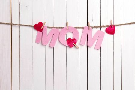 粉红色的字母妈妈挂在 clothespins 的白色木质背景
