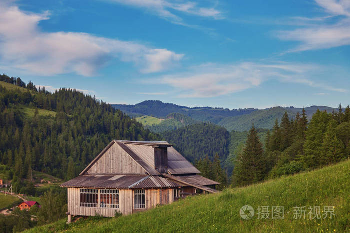 山上绿色草地上的一座木屋老森林附近的一所房子在这个村庄的生活方式