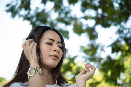 一个微笑的女孩的肖像听音乐, 而放松自然公园户外