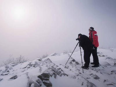 两个人在雪山上享受冬天的 photographying。自然摄影师