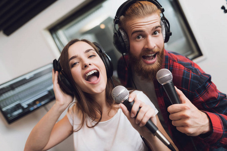 一个男人和一个女人在现代录音棚里唱一首歌。在男人是一个红色的检查衬衫, 一个女人的白色 t恤