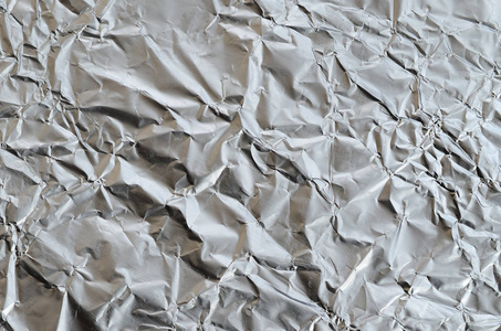 薄皱板破碎锡铝银箔背景与光泽皱巴巴的表面纹理