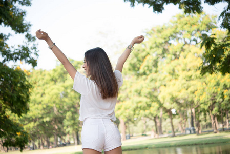 少女在公园里举起双臂和欢笑的画像