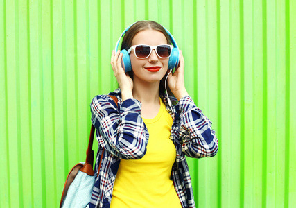 快乐的酷女孩在听音乐耳机在绿色的背景和目标