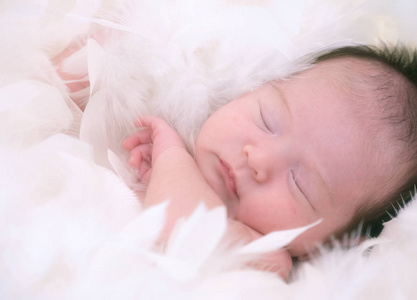 新生女婴睡在白色毛皮毯子上