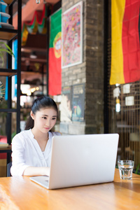 漂亮的时髦女子在咖啡厅使用便携式计算机