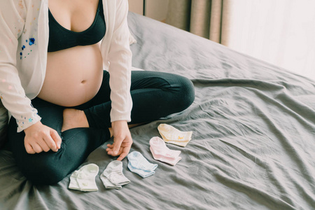 孕妇的腹部与手选择婴儿袜