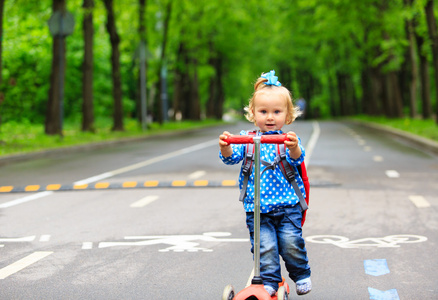 在城市的可爱小孩女孩骑滑板车
